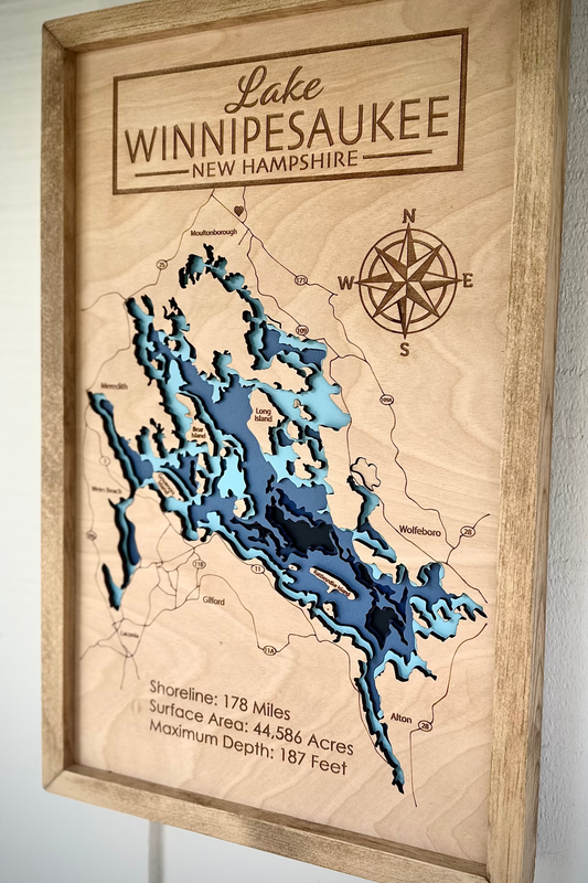 Wooden map of Lake Winnipesaukee, New Hampshire with a compass and lake depth details.